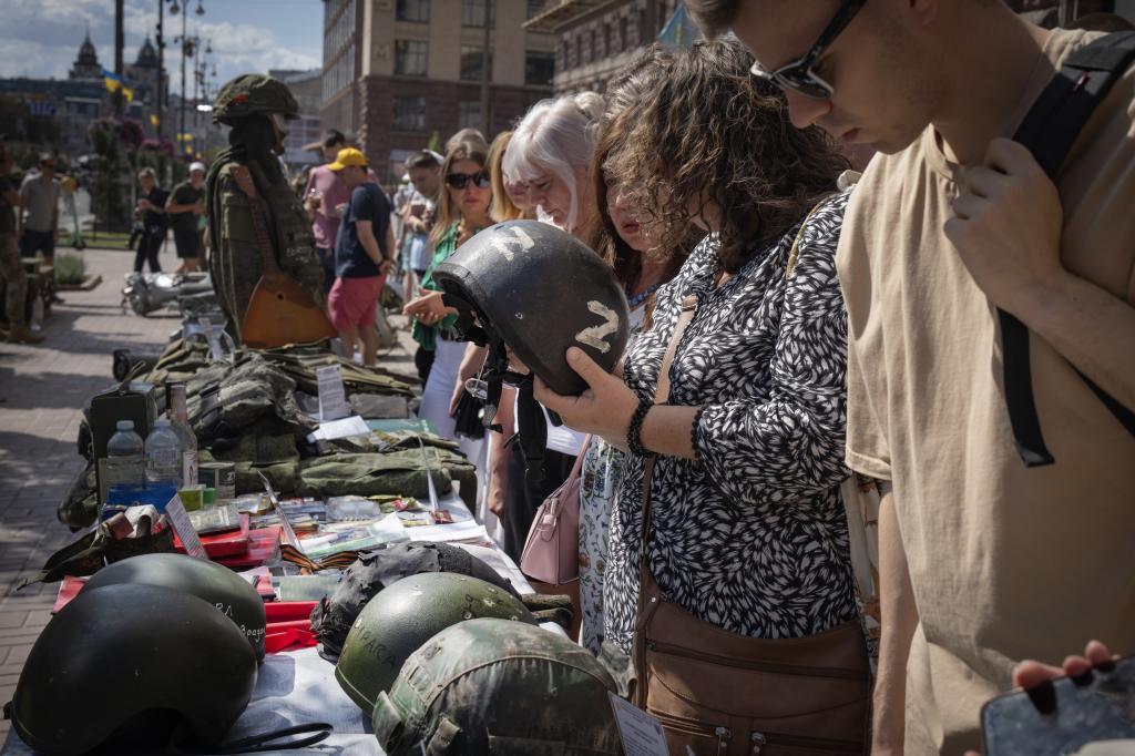 People look at equipment belonging to captured Russian soldiers