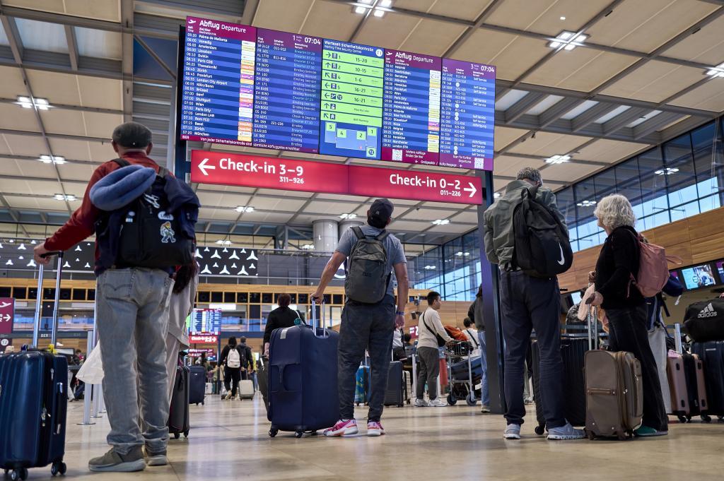 Passengers are seen in front of the check-in counters in Terminal 1 at Berlin Brandenburg Airport