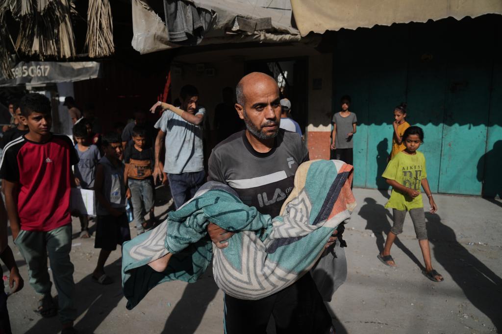 A Palestinian man carries the body of Hassan Nasr, 12, who was killed by an Israeli military strike