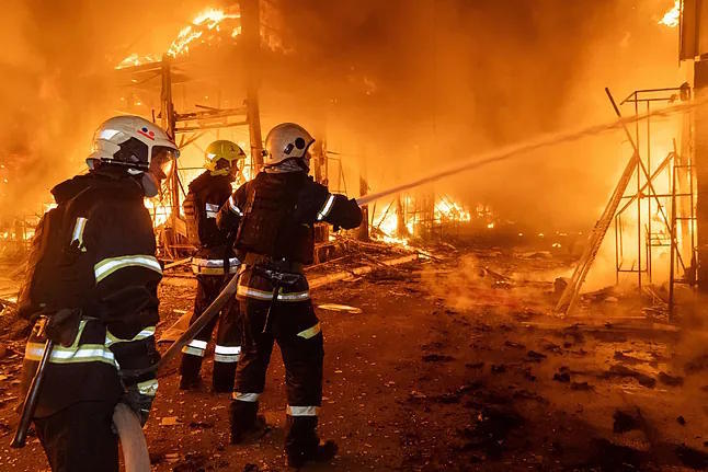 Several firefighters battle a fire caused by a Russian attack in Kharkiv.
