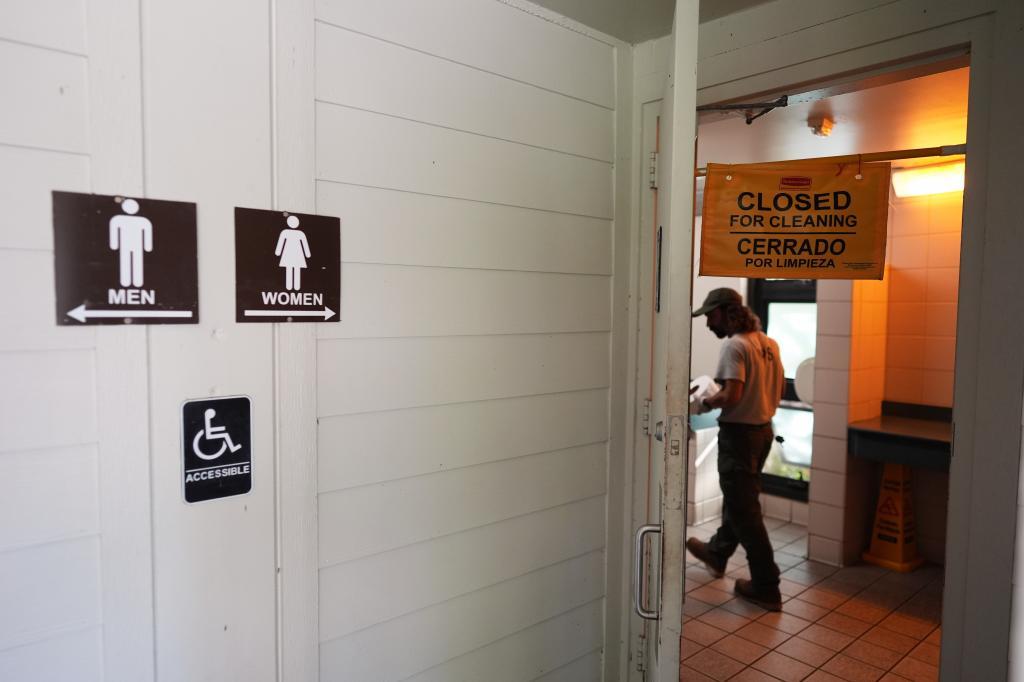 A park service employee cleans a bathroom outside the Ernest F. Coe Visitor Center