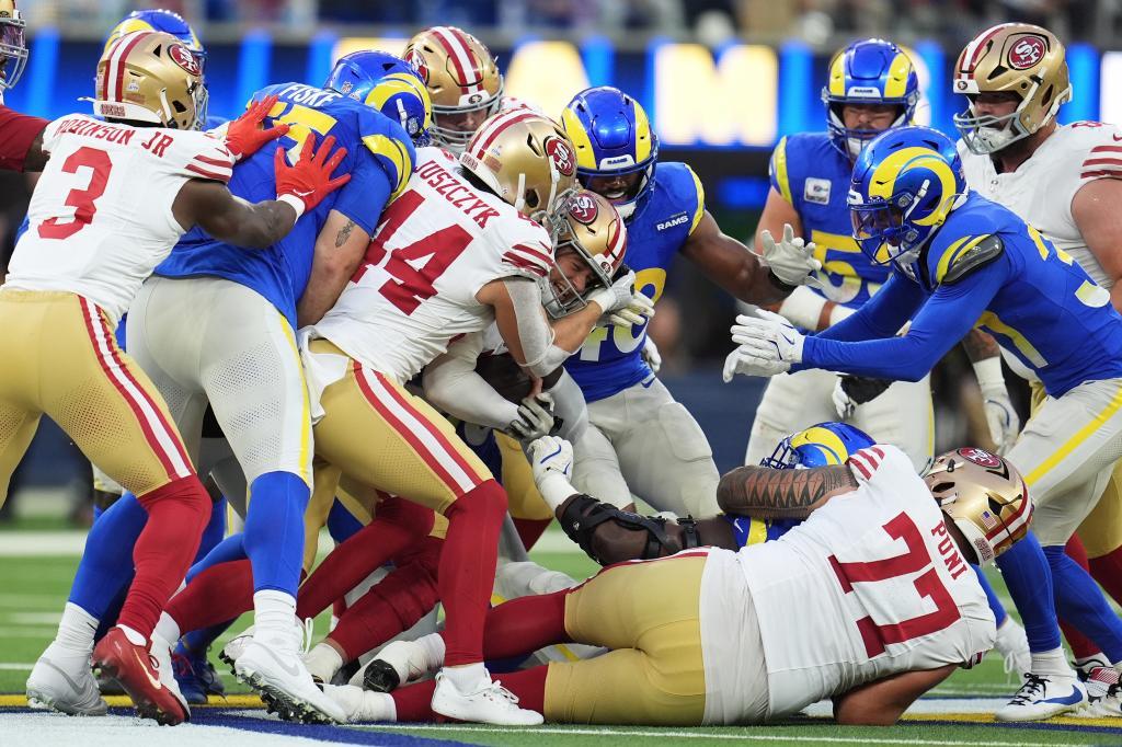 San Francisco 49ers quarterback Mac Jones, middle, runs for a first down during the first half of an NFL football game against the Los Angeles Rams,