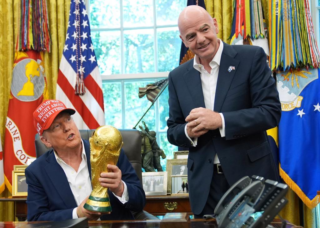 President Donald Trump holds the FIFA World Cup Winners Trophy as FIFA President Gianni Infantino
