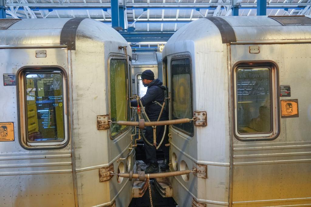 Train conductor walks between subway cars at a station in the Coney Island section