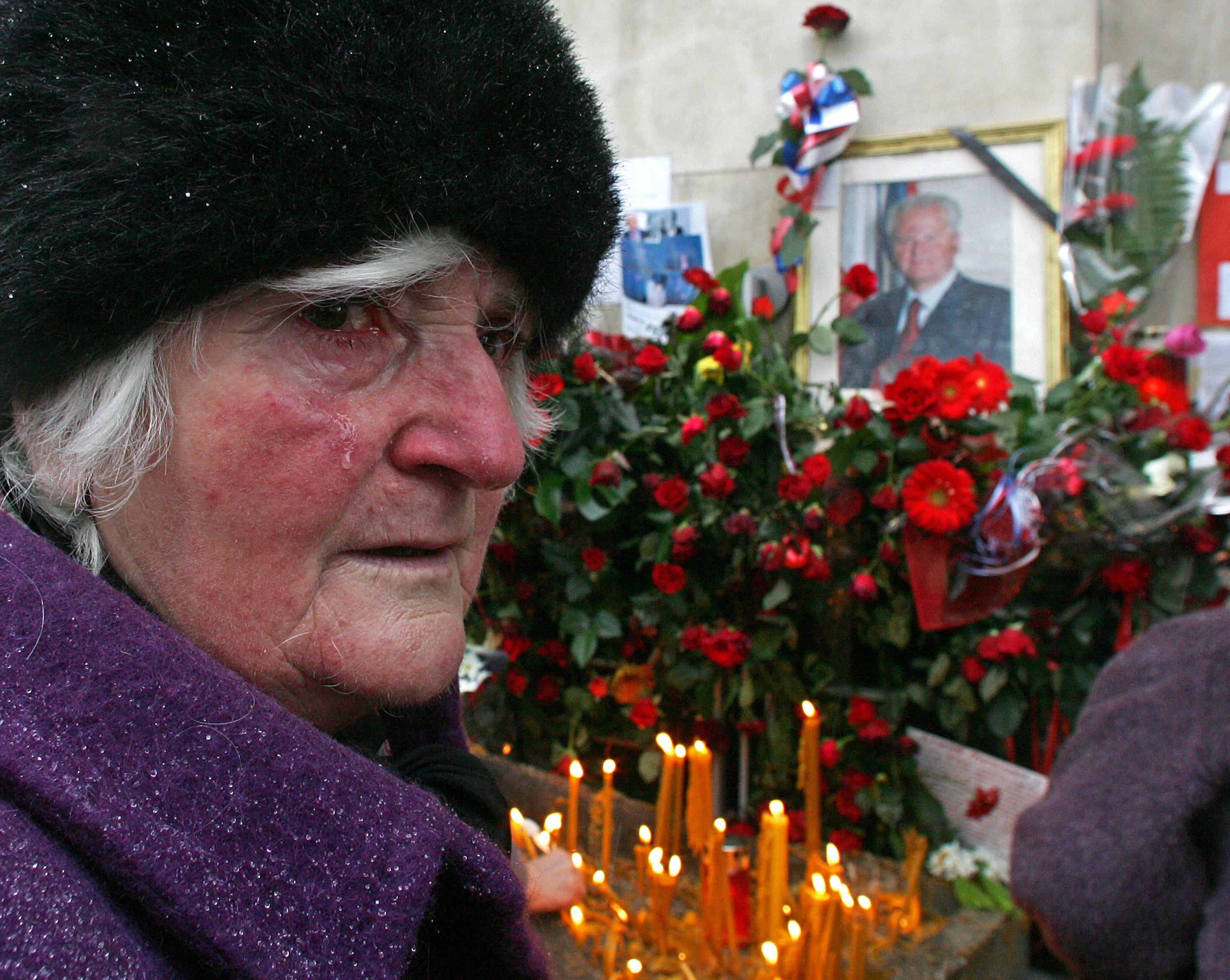 An elderly woman cries by a photo showing late president Milosevic in 2006.