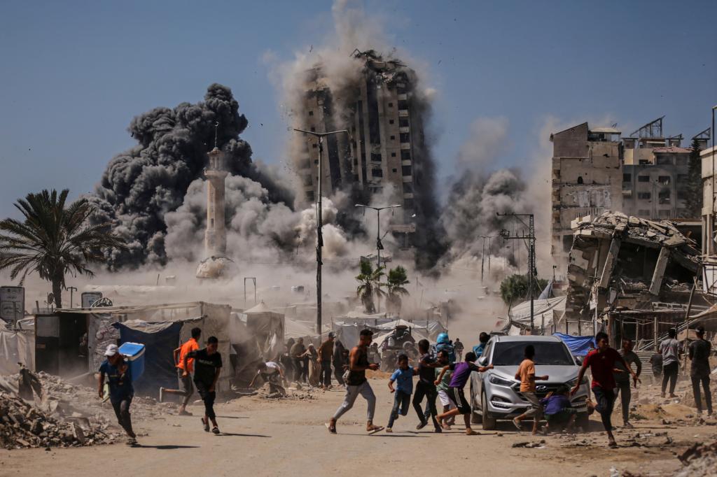 People run for cover during an Israeli attack on a high-rise building in Gaza City.