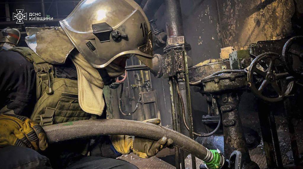 An emergency worker extinguishes a fire after a Russian attack on the Trypilska thermal power plant