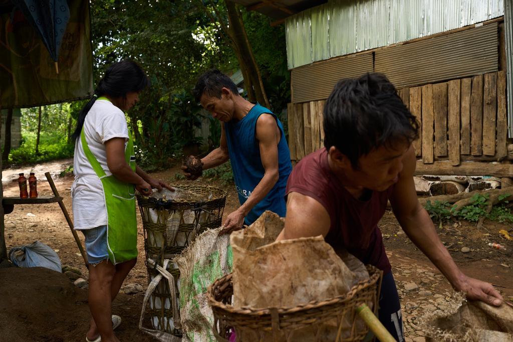 Two men sell yams they foraged in a forest near the Mae La refugee camp to a shop owner in the Tak province of Thailand