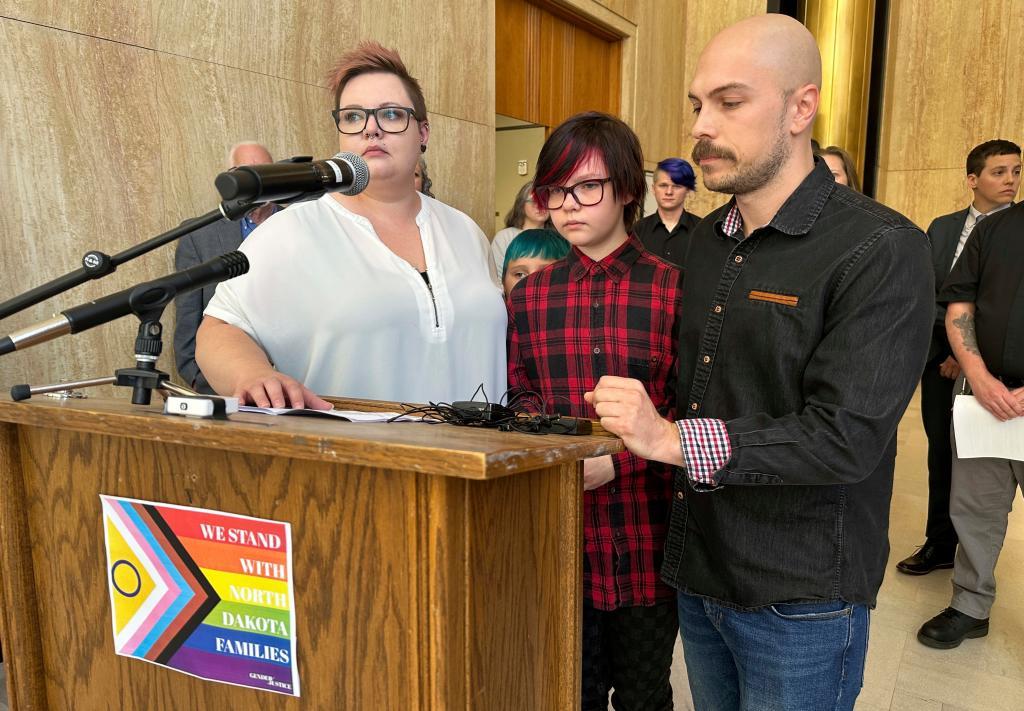 Parents Devon and Robert Dolney, stand with their child, Tate, center, during a news conference