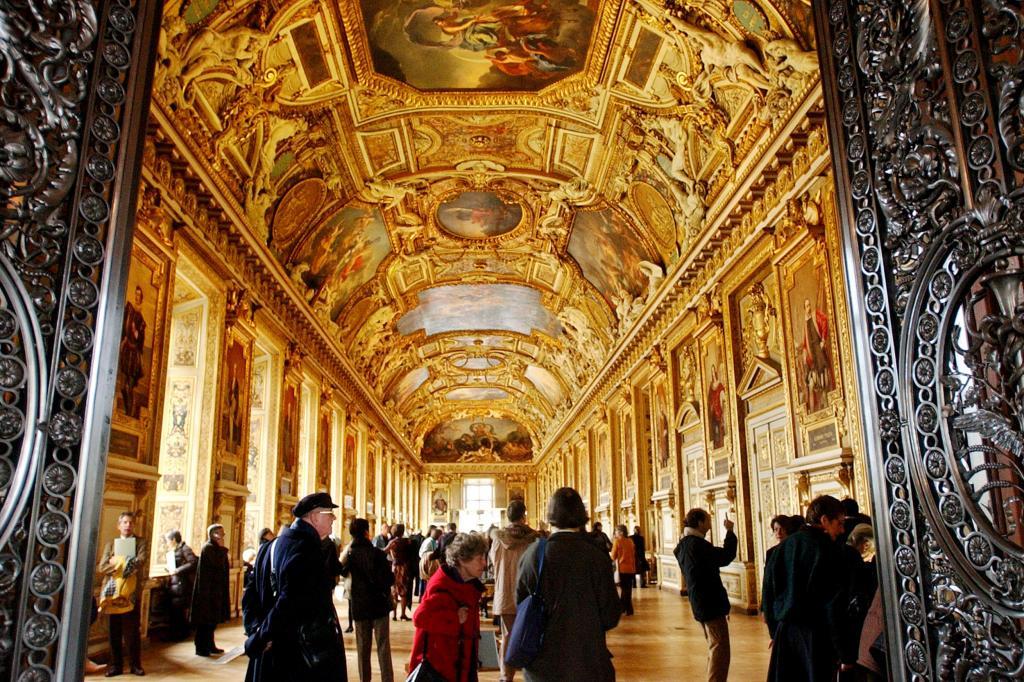 Visitors walks through the Apollo gallery of the Louvre museum after its renovation,