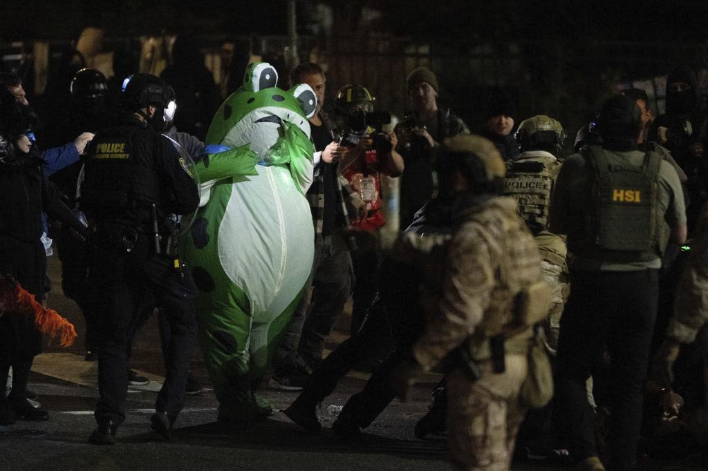 Seth Todd, dressed in an inflatable costume, watches as Department of Homeland Security officers detain a protester