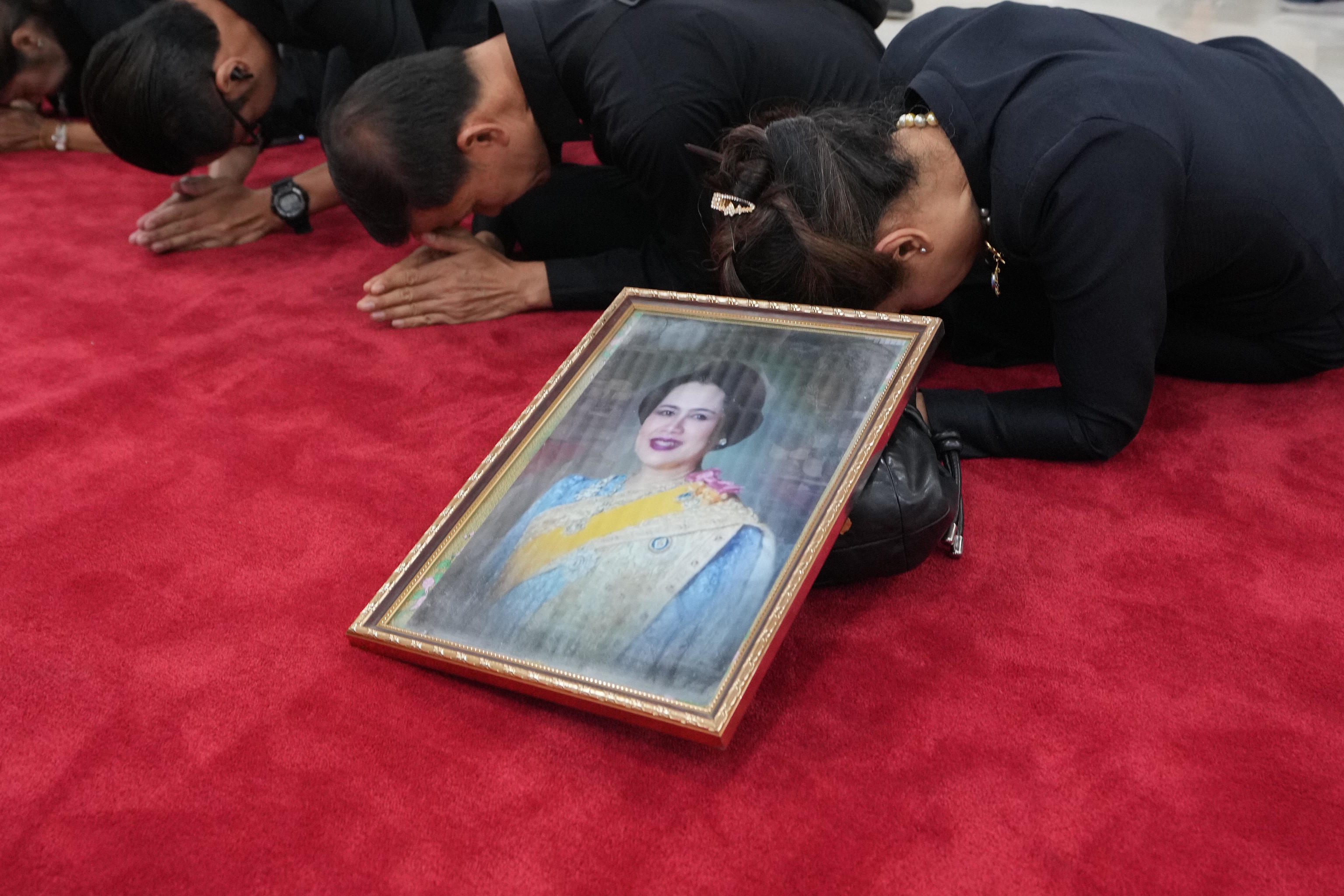 Mourners pray their respects near a portrait of Queen Mother Sirikit.