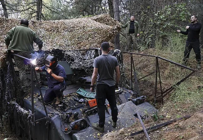 Members of the 65th Mechanized Brigade repair an anti-drone protection system.