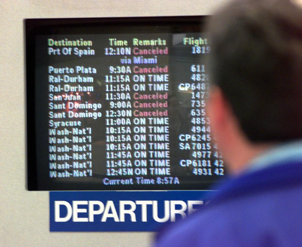 A passenger looks at the screen with canceled flights at J.F.K. Airport.