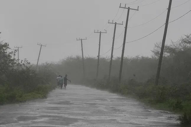 Several people walk along a road during the passage of Hurricane Melissa in Rocky Point, Jamaica.