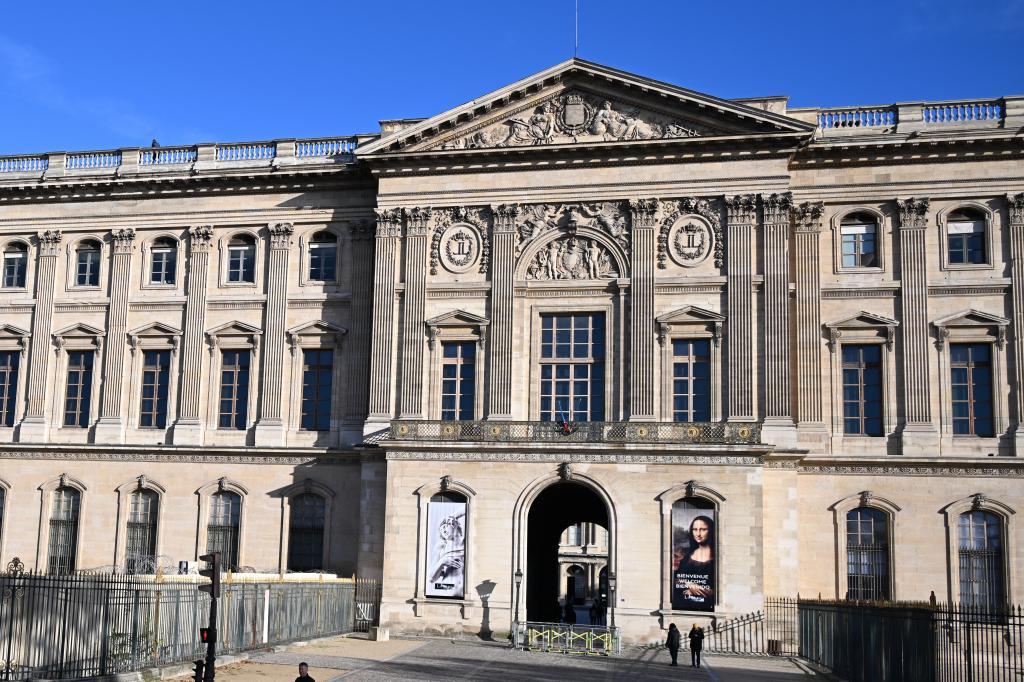 People walk by an entrance of the Louvre museum.