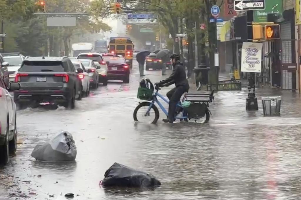A cyclist rides through floodwaters during a rainstorm in New York