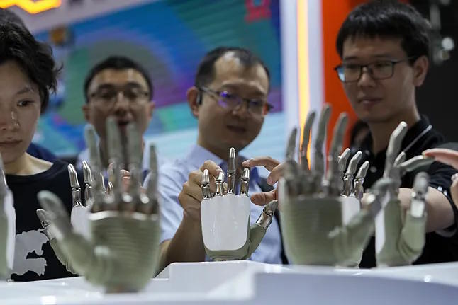 Visitors touch the hands of humanoid robots at a booth during the World AI Conference in Shanghai.