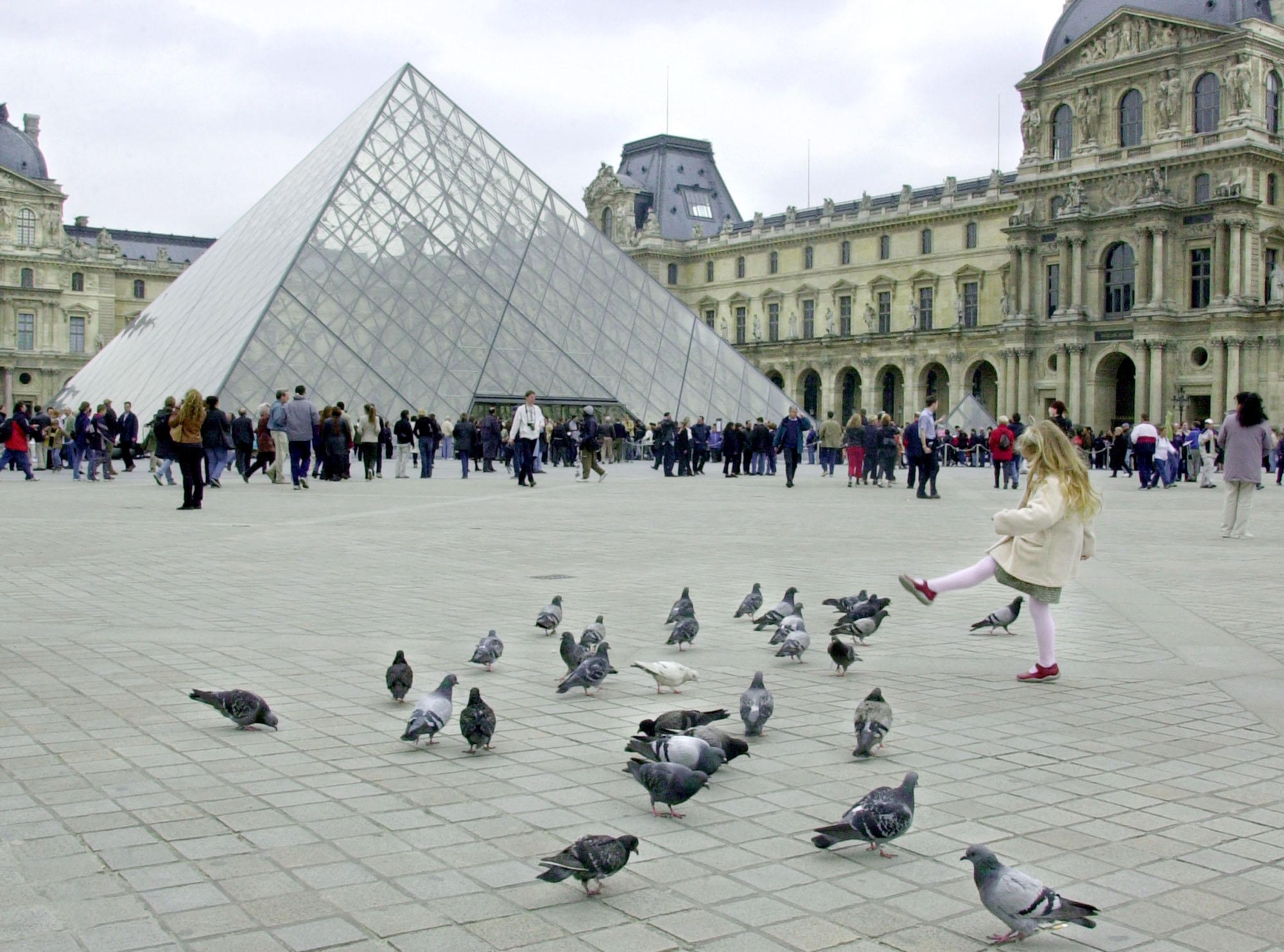 Tourists queue to enter the Louvre Museum.