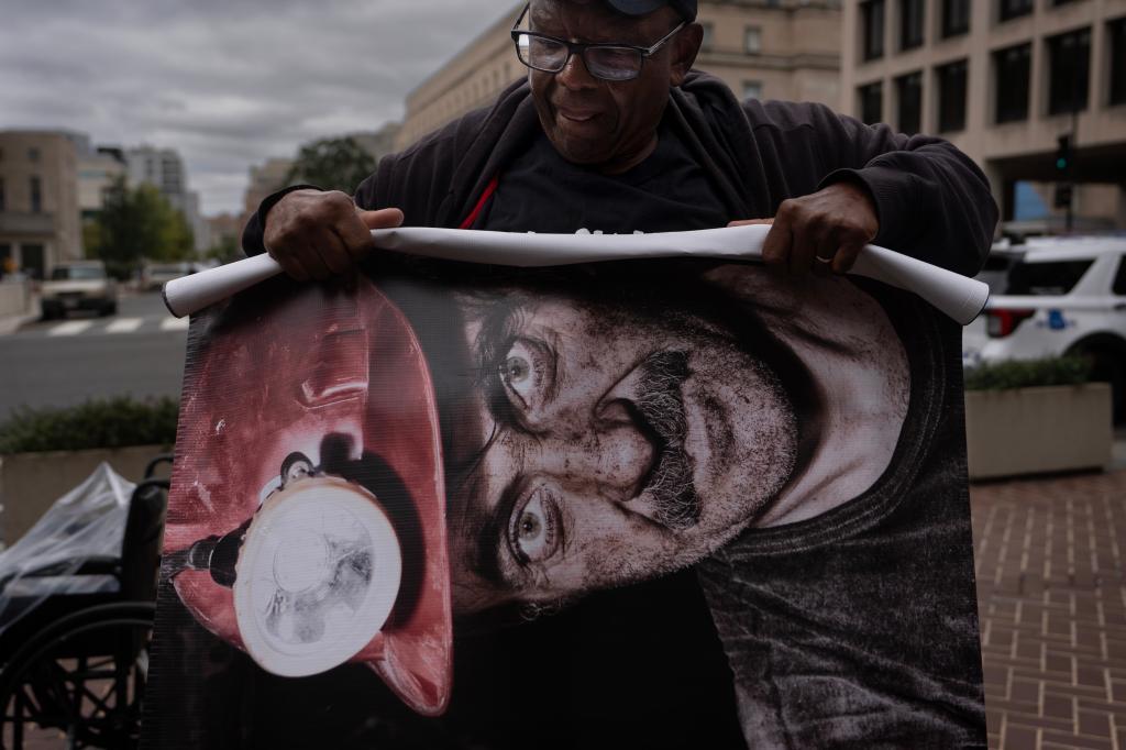 Roosevelt Neal, with the Fayette County Black Lung Association in W.Va., rolls up a banner of a coal miner who died of black lung disease