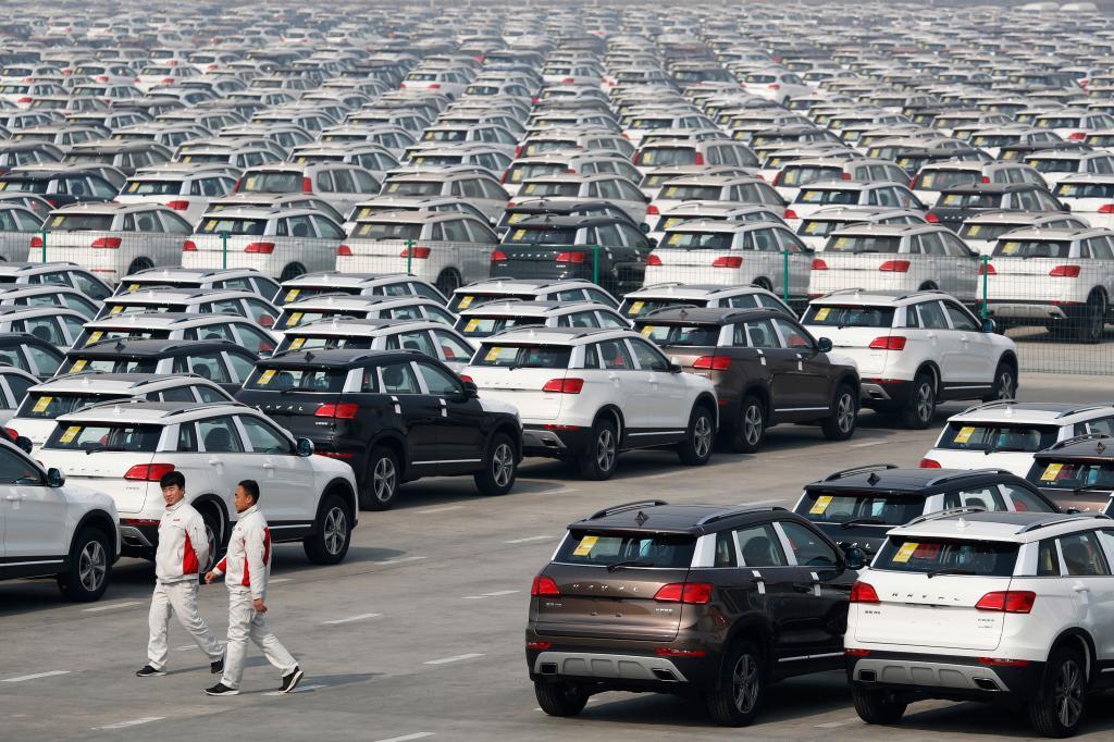 Workers walk past Haval SUV models parked outside the Great Wall Motors assembly plant