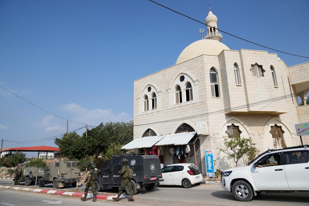 Israeli army inspectors tour a mosque that was torched and defaced by Israeli settlers overnight