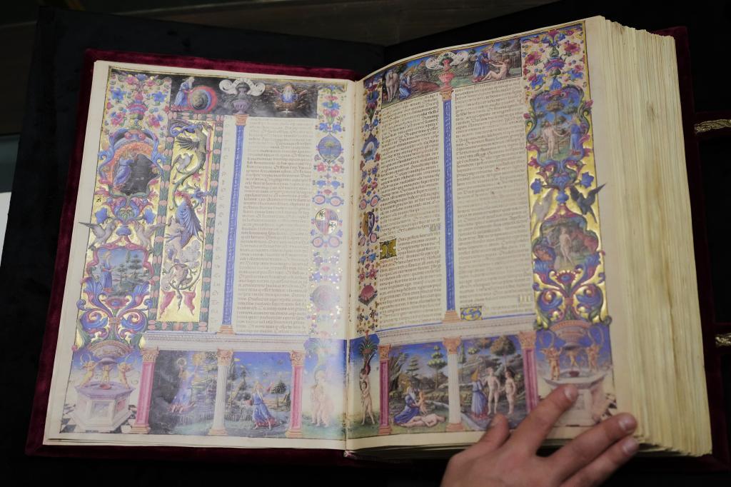 A journalist flips through a faithful reproduction of the 15th century Borso D'Este Bible
