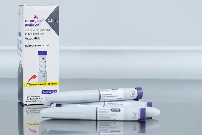 A container and two pens of the drug tirzepatide, marketed as Mounjaro by Eli Lilly.