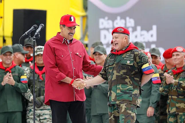 Maduro shakes hands with Venezuelan Interior Minister Diosdado Cabello.