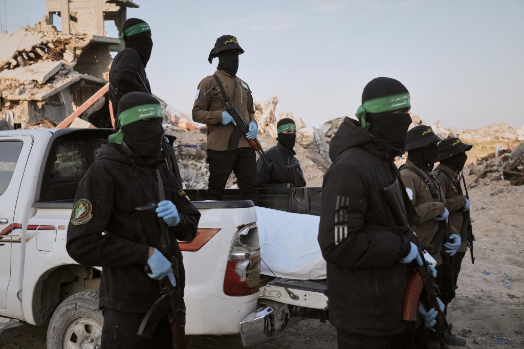 Masked Islamic Jihad and Hamas militants hand over a body bag