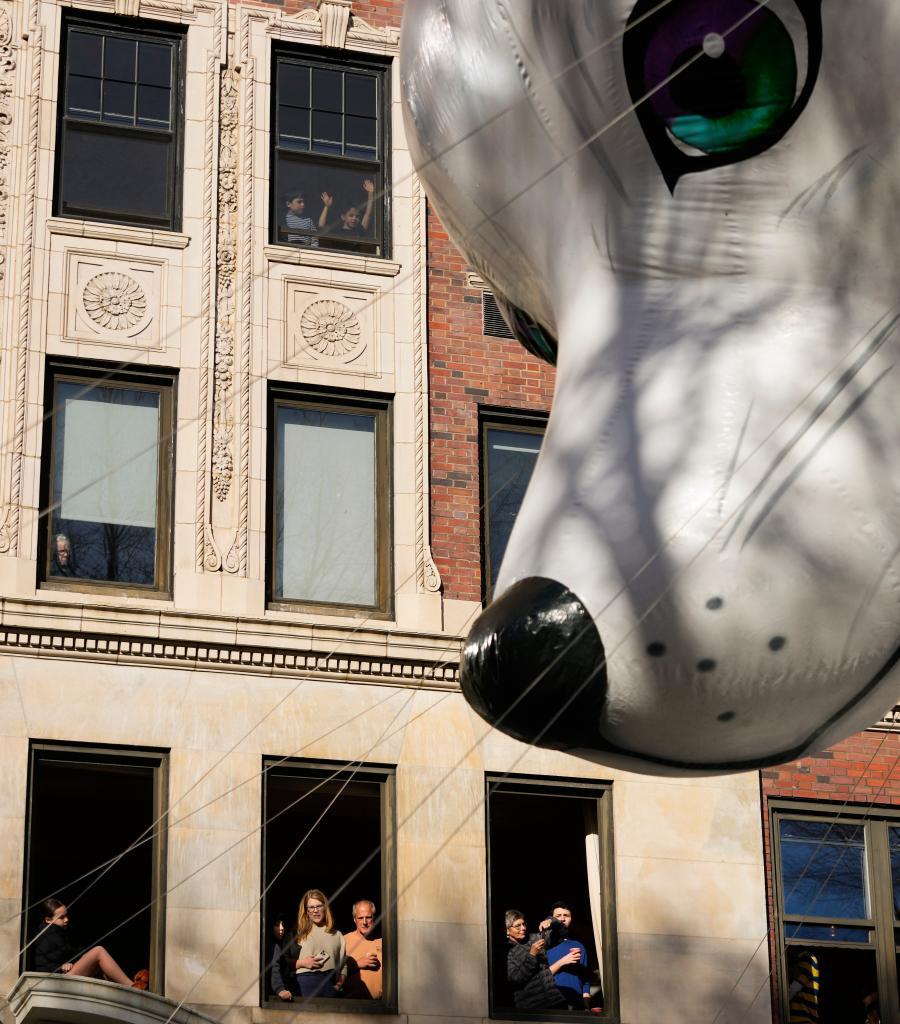 Spectators watch from their apartment windows as the Noorah balloon floats by down Central Park West during the Macy's Thanksgiving Day Parade