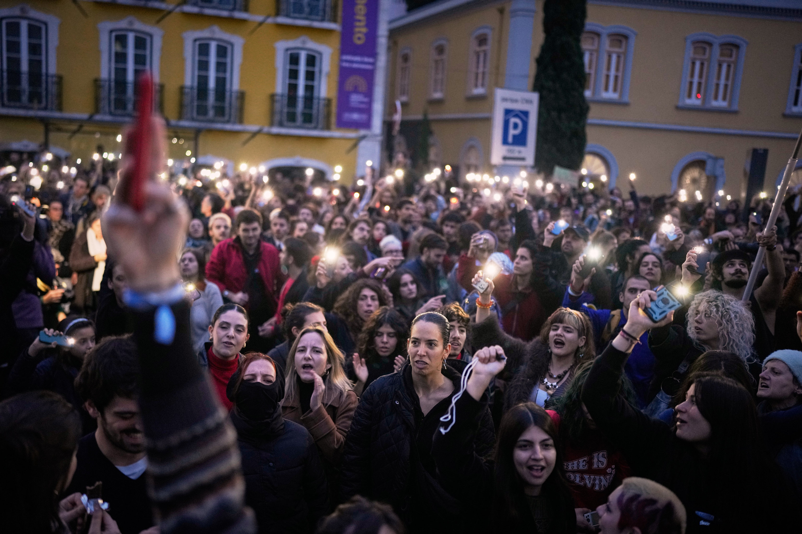 Demonstrators use the light from their cell phones as they gather outside the parliament.