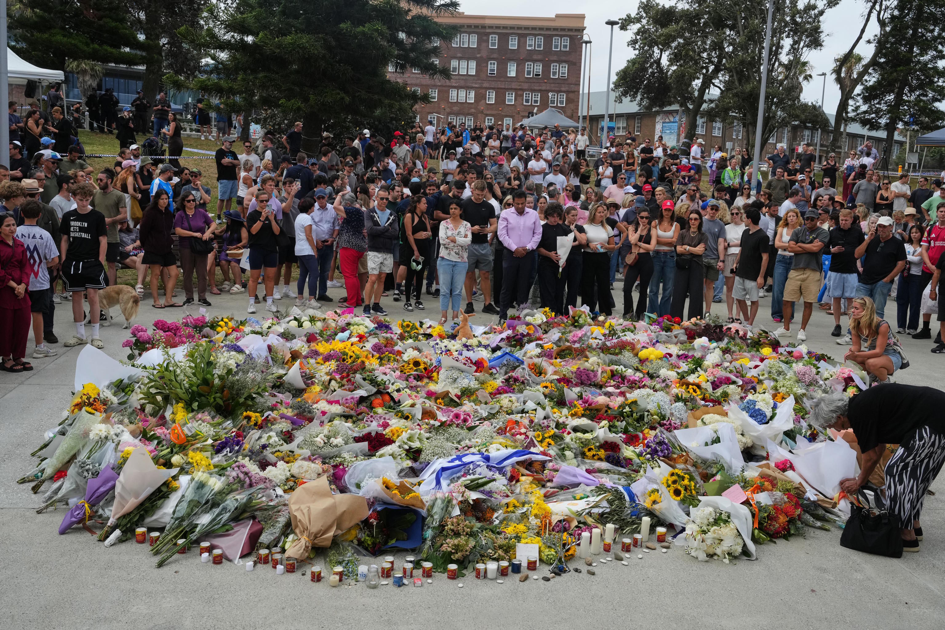 People gather around a tribute for shooting victims outside the Bondi Pavilion.