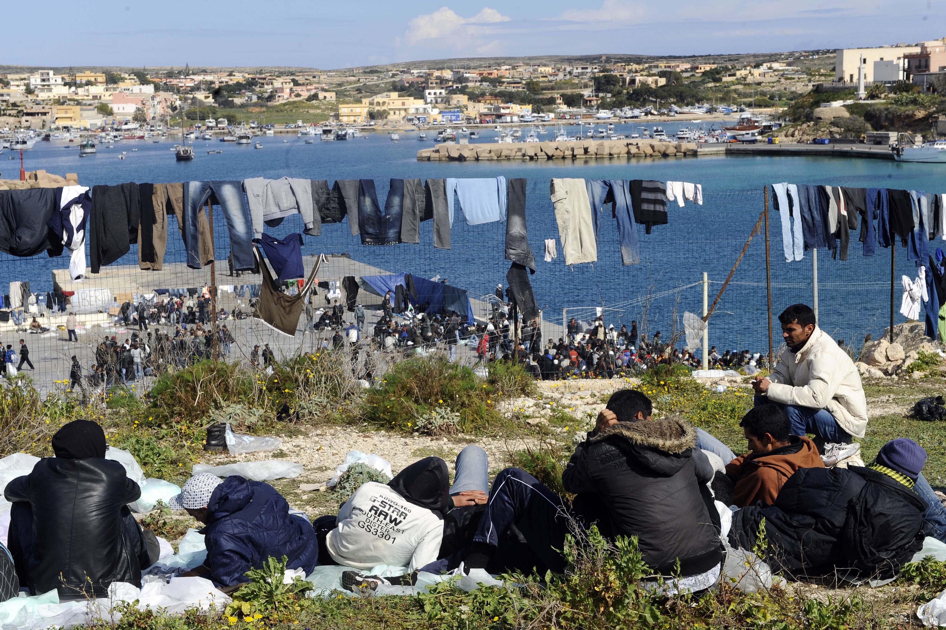 Migrants sit and take some rest on the tiny island of Lampedusa, Italy.
