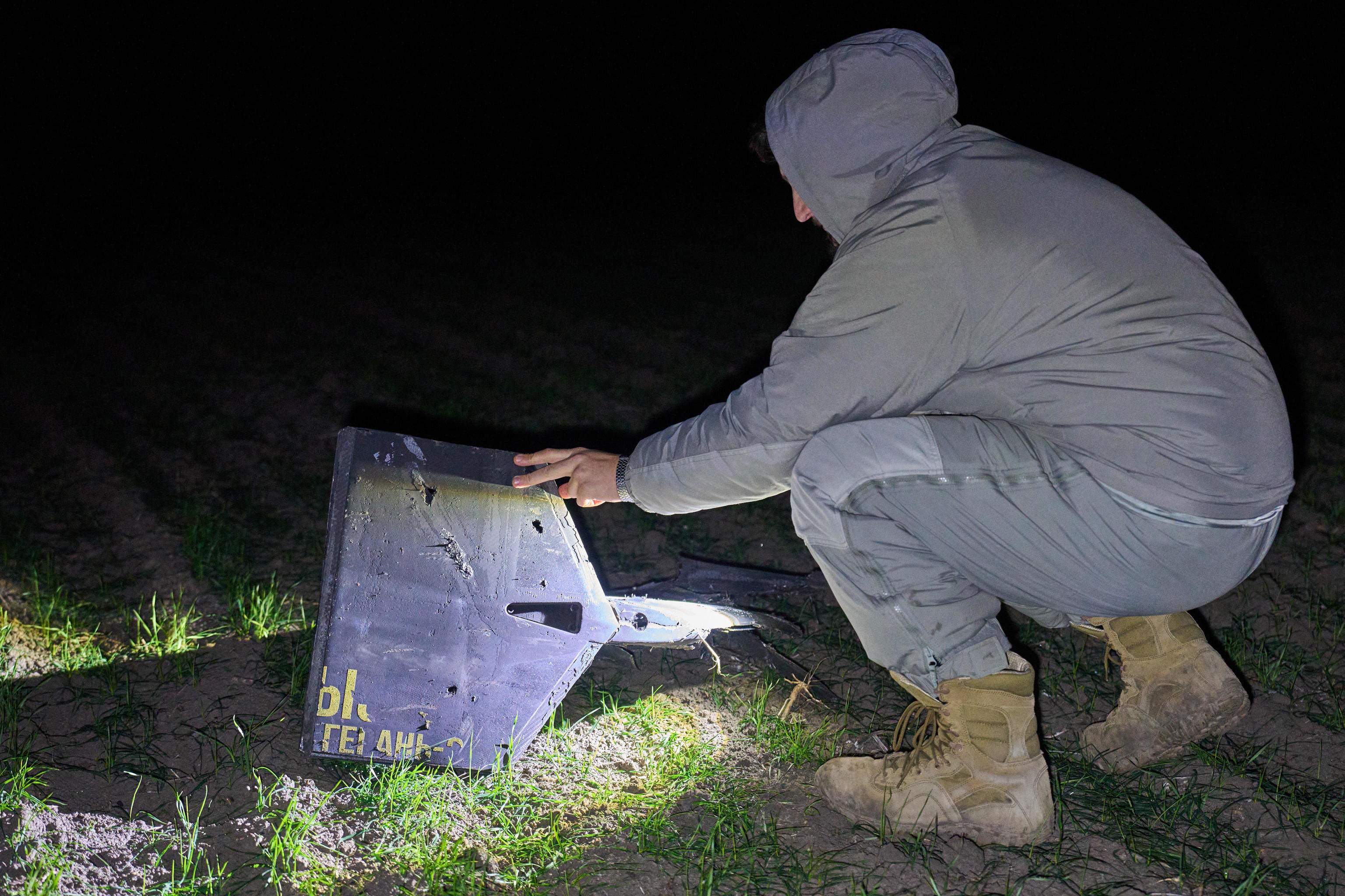 A Ukrainian soldier inspects fragments of a Russian Shahed drone.