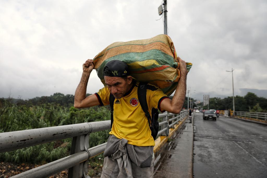 A man hauls a bag of goods on his shoulders as he crosses the Colombian-Venezuelan border