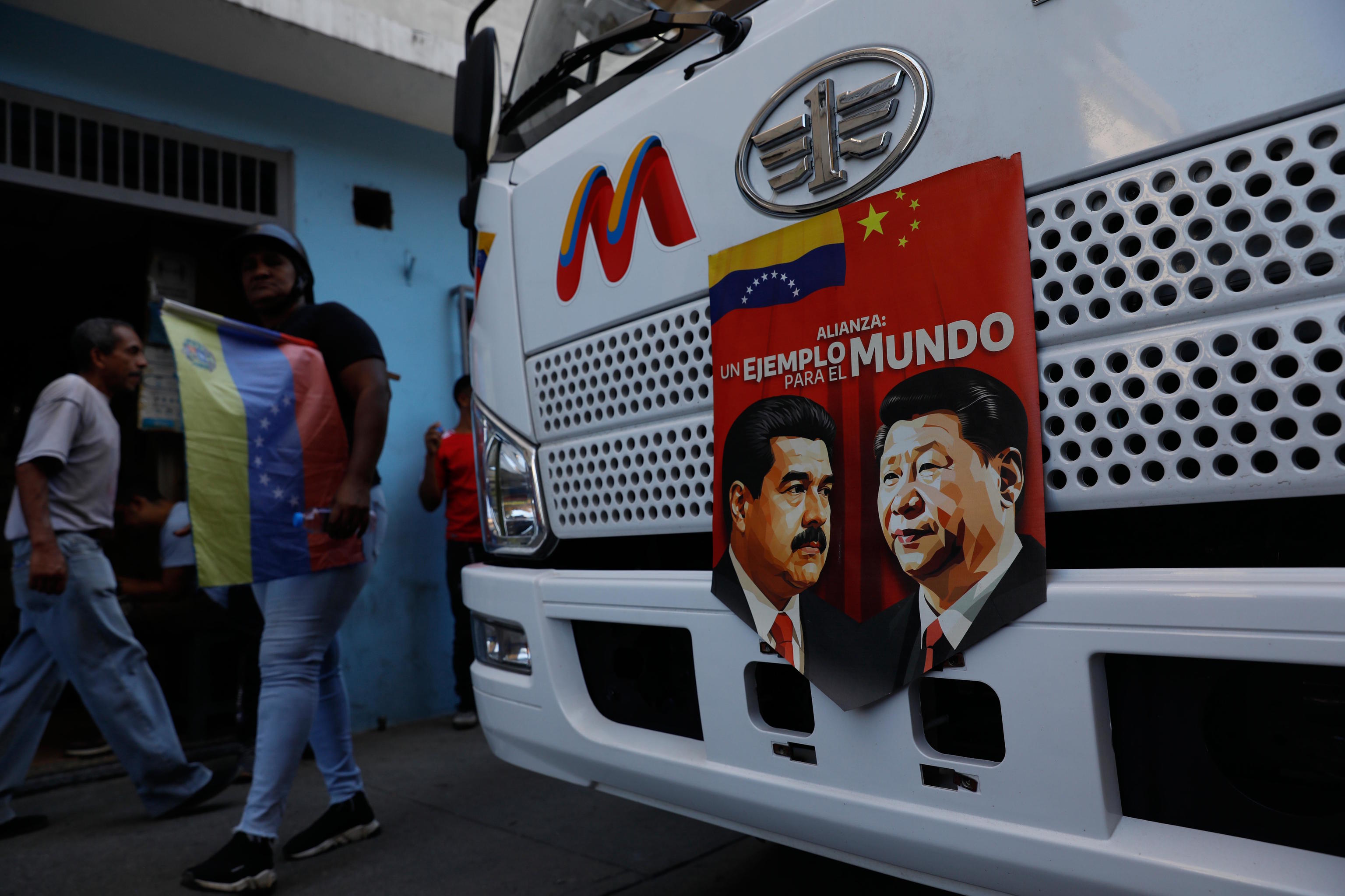 A banner on the front end of a bus features images of Maduro and Xi Jinping.