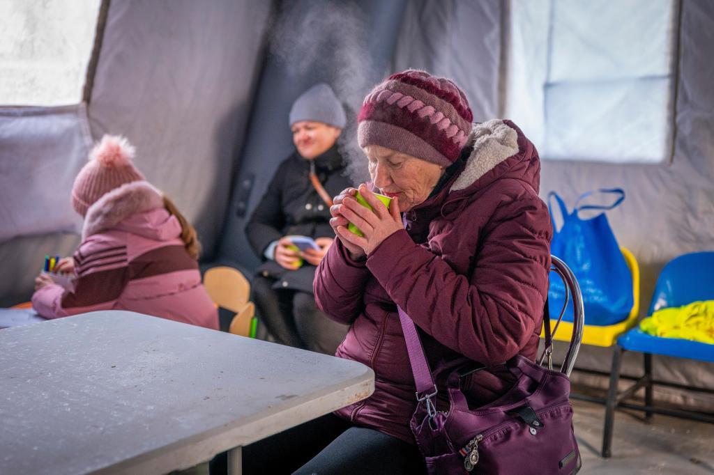 A woman gets warm with a hot cup of tea at an emergency center set up