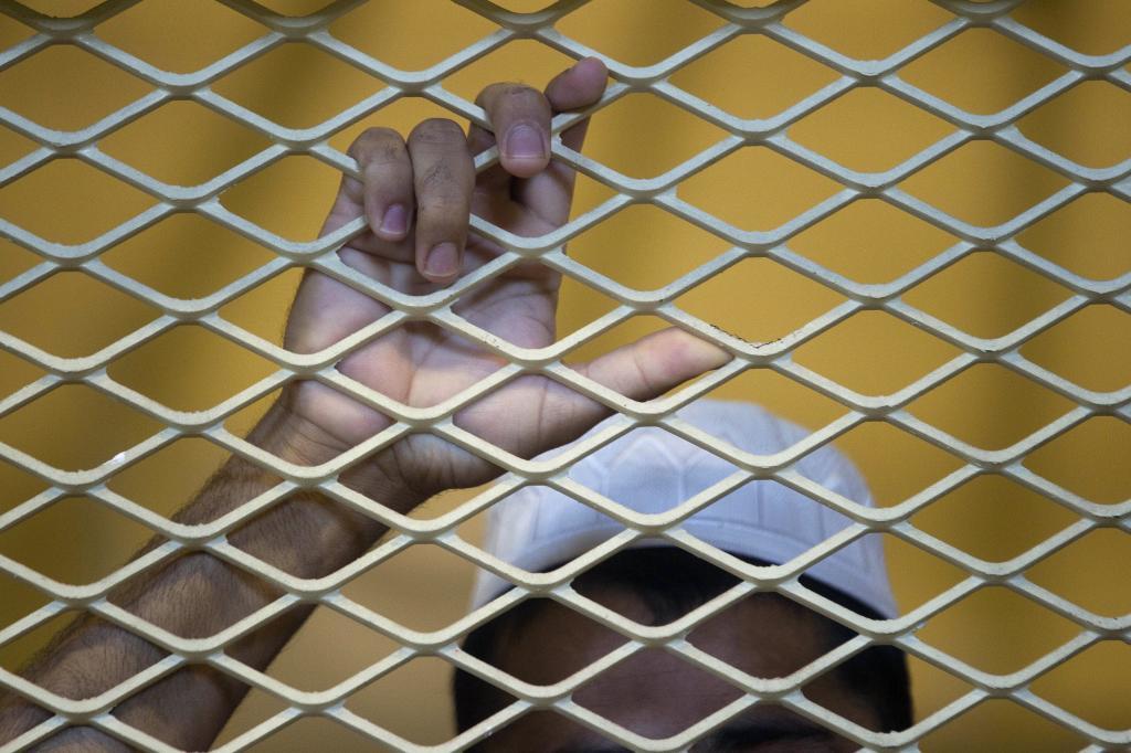 A prisoner leans on the bars inside the detention center.
