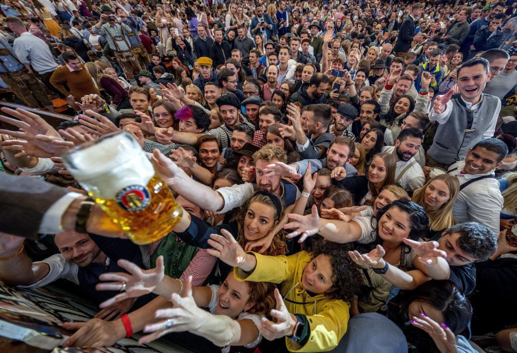 Young people reach out for free beer in one of the beer tents on the opening day of the 187th Oktoberfest beer festival in Munich