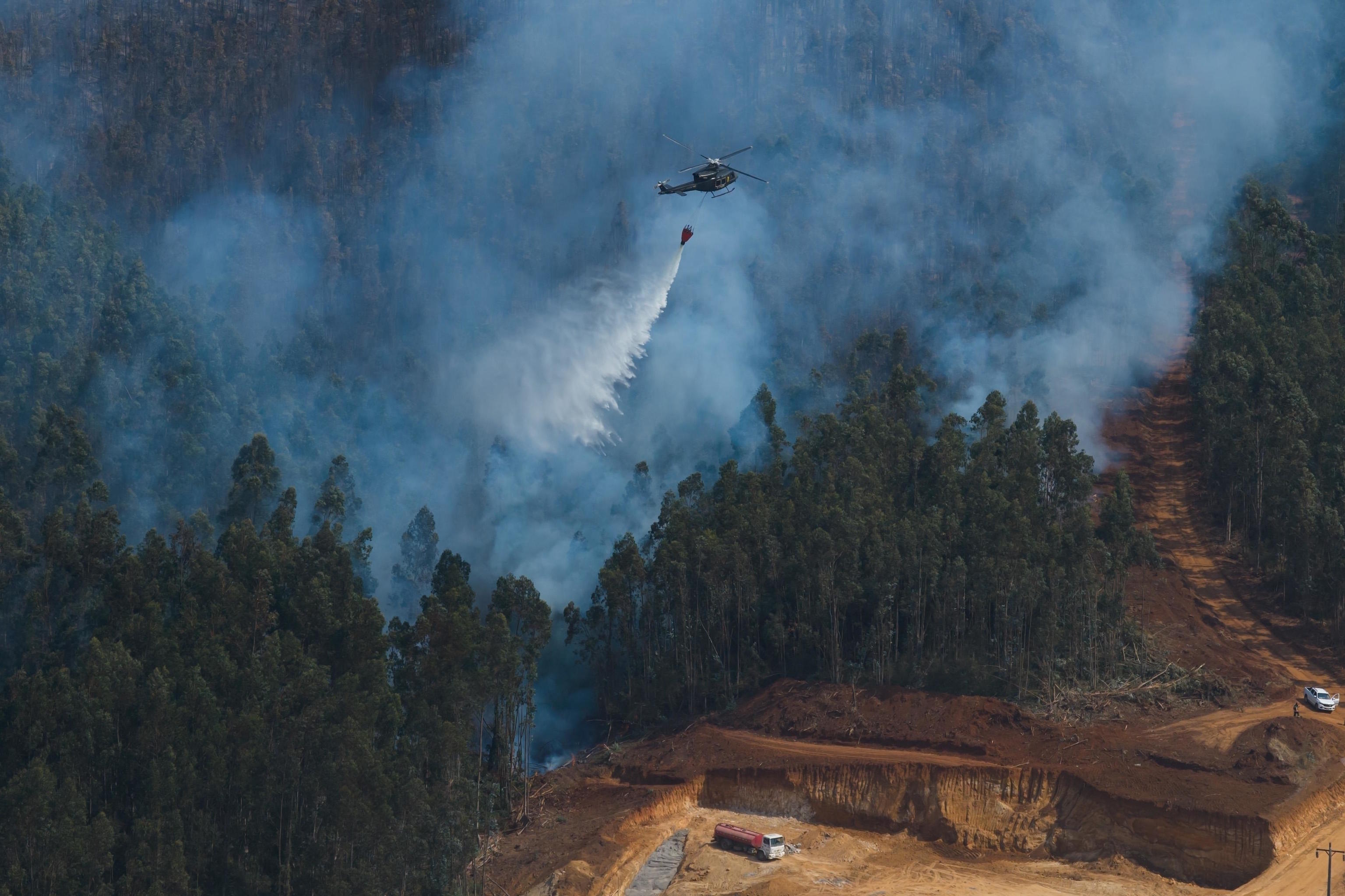A helicopter drops water to fight forest fires near Concepción.