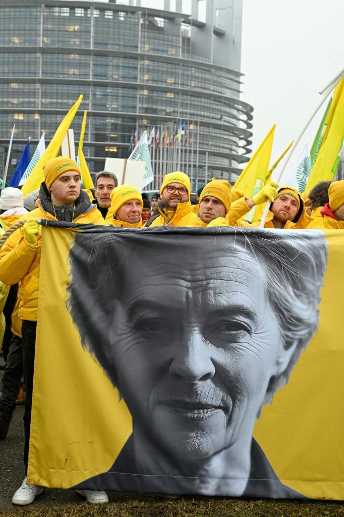 Farmers protest, as they stand in front of a banner of European Commission President Ursula von der Leyen.