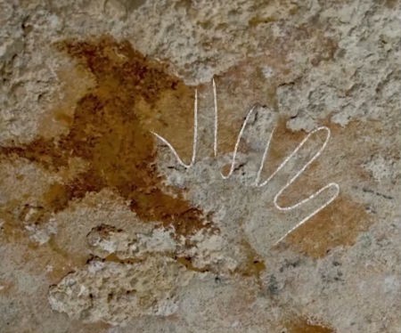 Hands blurred behind more modern cave paintings