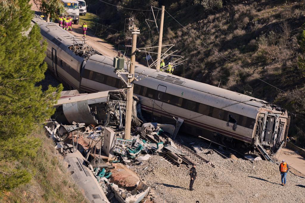 Guardia Civil officers collect evidence next to the wreckage of train cars involved in a collision in Adamuz