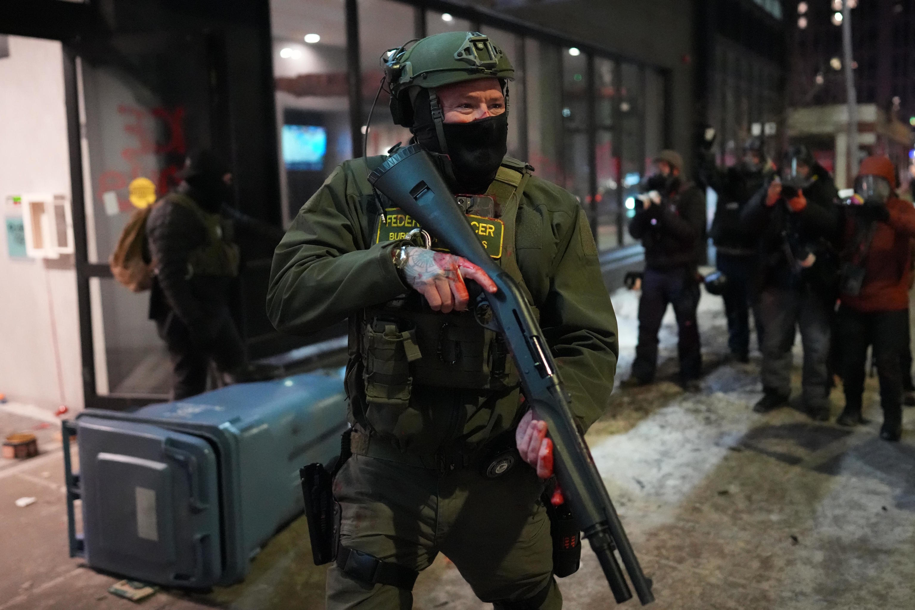 A federal agent stands guard near a hotel during a noise demonstration protest.