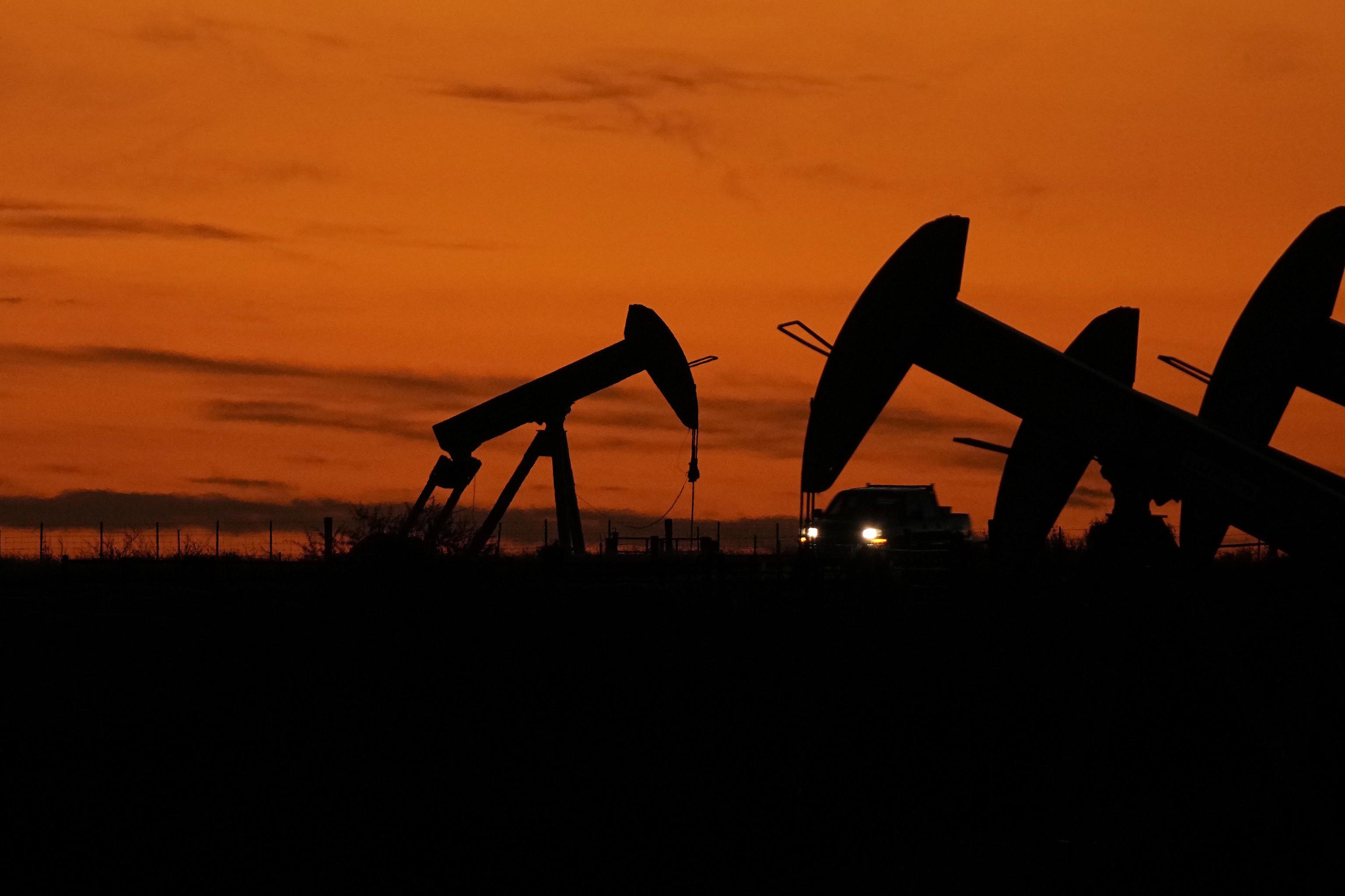 A truck passes oil pump jacks at dusk near Karnes City, Texas.