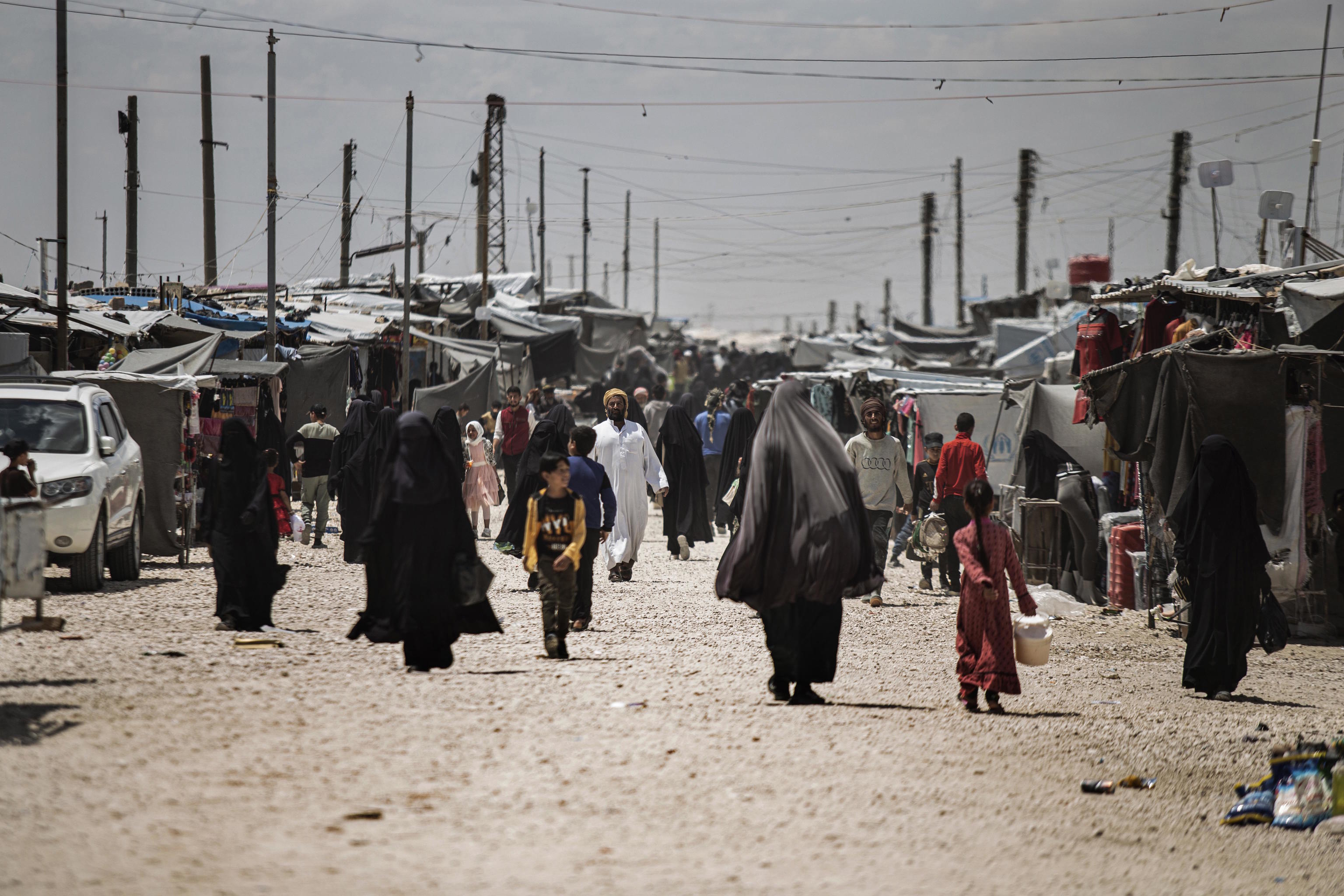 Family members of suspected Islamic State group fighters walk at al-Hol camp.