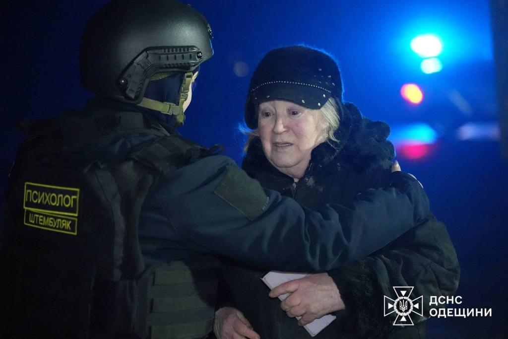 A rescuer calms down an elderly woman after a Russian drone ruined an apartment building