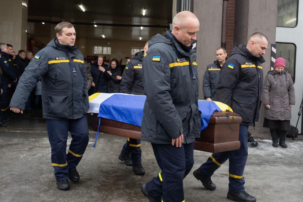 Rescuers carry the coffin of their fellow Oleksandr Zibrov, 36, who was killed in a secondary Russian drone strike on a residential building
