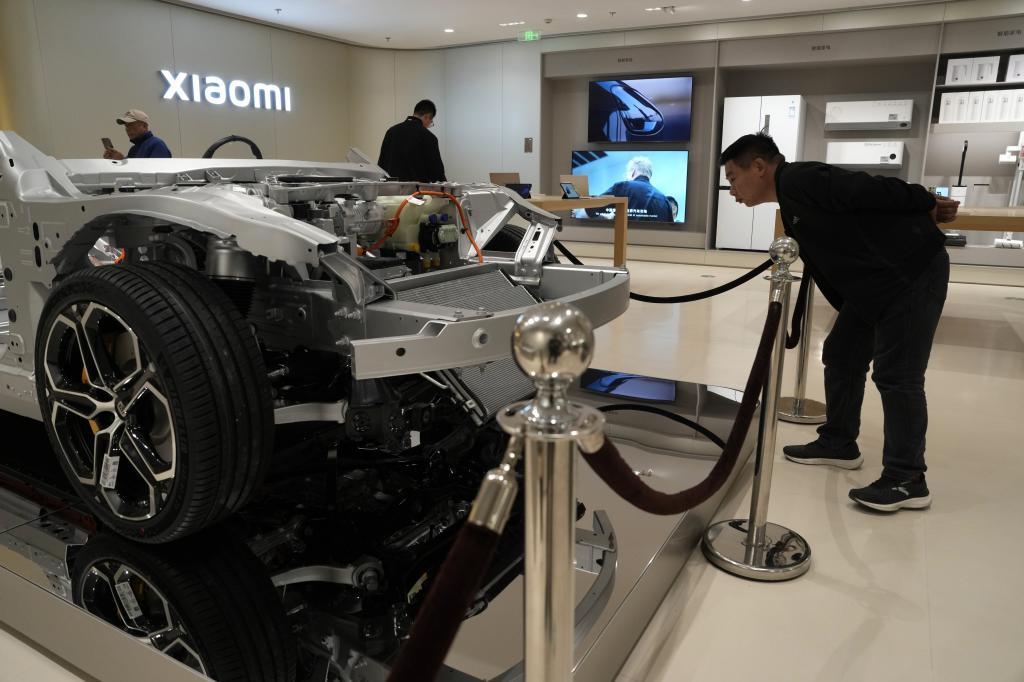 Visitors to the Xiaomi Automobile flagship store look at the interiors of a Xiaomi SU7 electric car